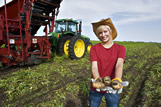 Girl holding potatoes next to harvest equipment